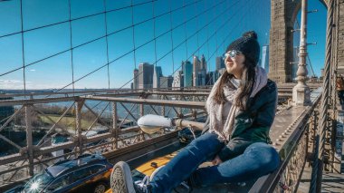 Genç ve pervasız kız Brooklyn Köprüsü'nün New York kenarında oturur