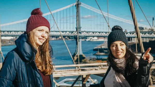 二人の女の子がニューヨークの有名なブルックリン橋を渡って歩く — ストック写真