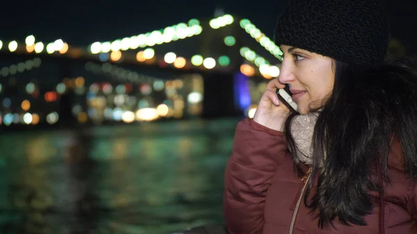 Una joven recibe una llamada en el puente de Brooklyn por la noche — Foto de Stock