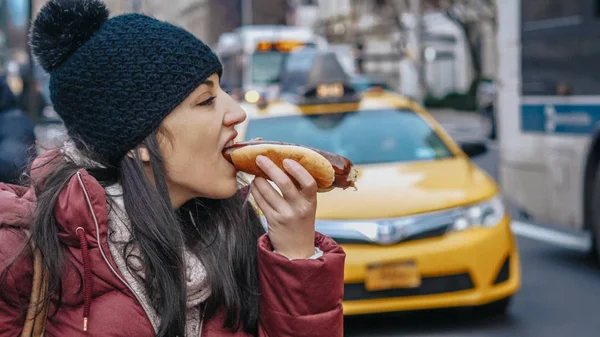 Młoda kobieta zjada hot doga na ulicach Nowego Jorku — Zdjęcie stockowe