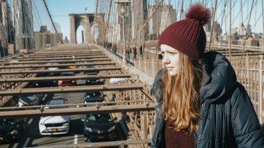 Güzel kız yürüyüş Brooklyn Köprüsü'nün New York üzerinden hoşlanır.