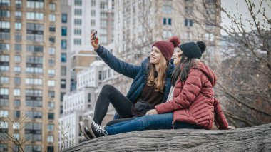 İki kız bir kaya Central Park New York'ta oturmak