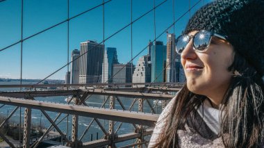 Genç güzel kadın üzerinde Brooklyn Köprüsü'nün New York güzel bir güneşli gün sahiptir