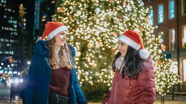 Two girls in front of a Christmas tree enjoy the wonderful time in New York — Stock Photo, Image