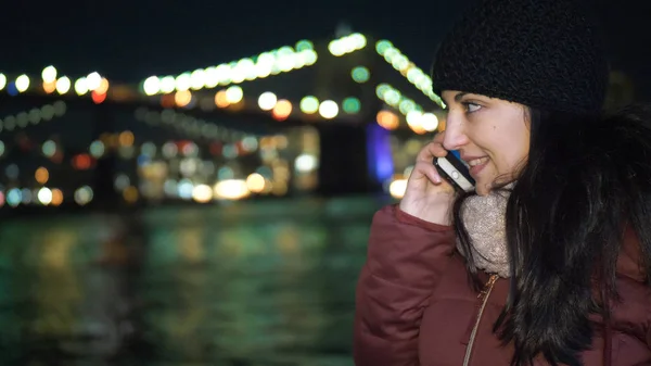 Young woman takes a phone call at Brooklyn Bridge by night — Stock Photo, Image