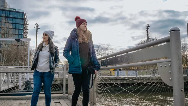 Två unga kvinnor i New York gå längs den typiska skyline på Brooklyn Bridge — Stockfoto