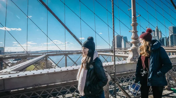 Two girls walk over the famous Brooklyn Bridge in New York — Stock Photo, Image