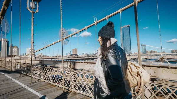 Mujer joven en Nueva York pasea por el puente de Brooklyn en un día soleado — Foto de Stock