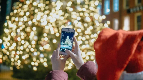 Young woman takes a photo of a huge Christmas tree in New York — Stock Photo, Image