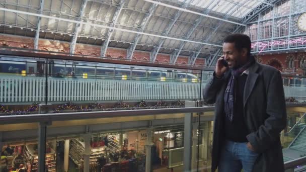 Zwarte zakenman neemt een telefoongesprek op een St Pancras Treinstation in Londen - Londen, Engeland - December 16, 2018 — Stockvideo