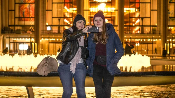 Deux filles passent une nuit incroyable à New York alors qu'elles sont assises à une fontaine - NEW YORK, États-Unis - 4 DÉCEMBRE 2018 — Photo
