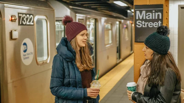 ニューヨークの地下鉄駅のプラットフォームで 2 人の女性を待つ電車 - ニューヨーク、アメリカ合衆国 - 2018 年 12 月 4 日 — ストック写真