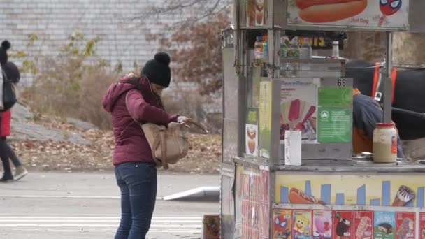 Una joven compra un perrito caliente en las calles de Nueva York — Vídeos de Stock