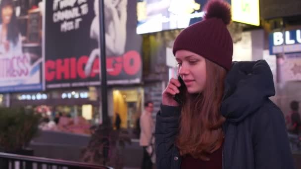 Una joven recibe una llamada en Times Square por la noche. — Vídeos de Stock