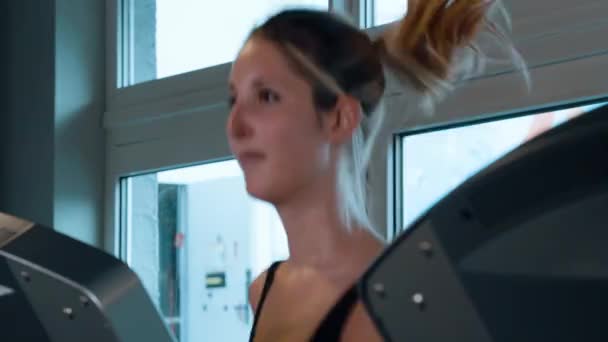 Flickan springer på ett löpband i gymmet — Stockvideo