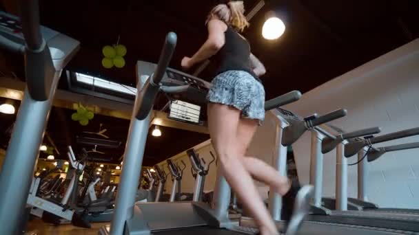A lány futópadon fut az edzőteremben. — Stock videók