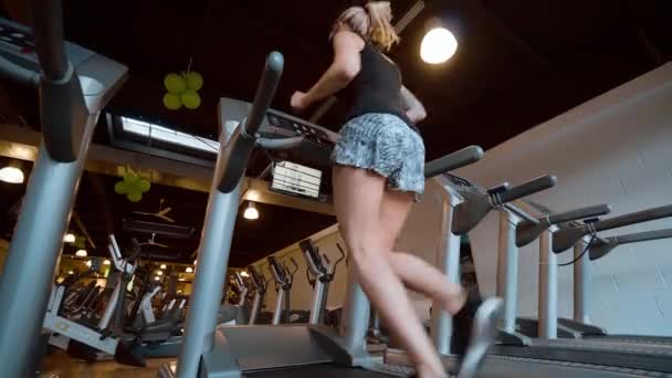 Chica corre en una cinta de correr en el gimnasio — Vídeo de stock