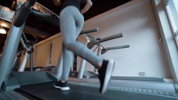 Дівчина біжить на біговій доріжці в спортзалі — стокове відео