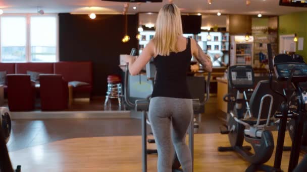 Young and sexy girl is running on a stepper at the gym — Stock Video