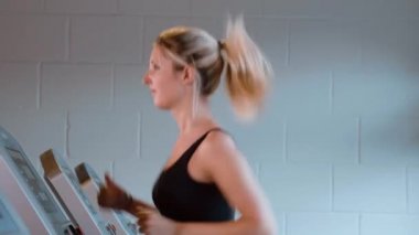 Kız spor salonunda koşu bandında koşuyor.