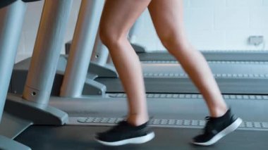 Kız spor salonunda koşu bandında koşuyor.
