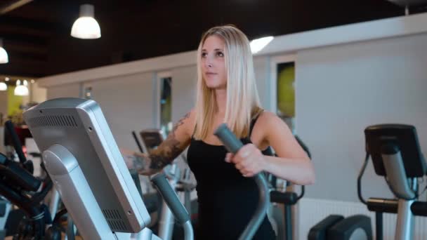 Joven y sexy chica está corriendo en un paso en el gimnasio — Vídeos de Stock