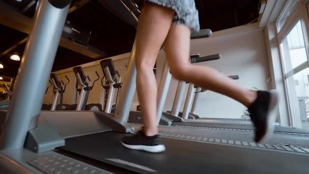 Chica corre en una cinta de correr en el gimnasio — Vídeos de Stock