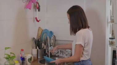 Genç kadın mutfakta bulaşık temizler