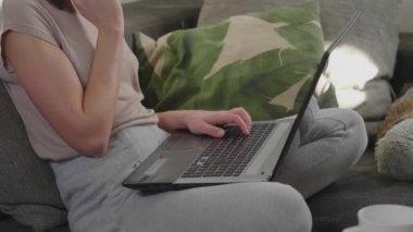 Genç kadın ev ofisinde laptopuyla çalışıyor.