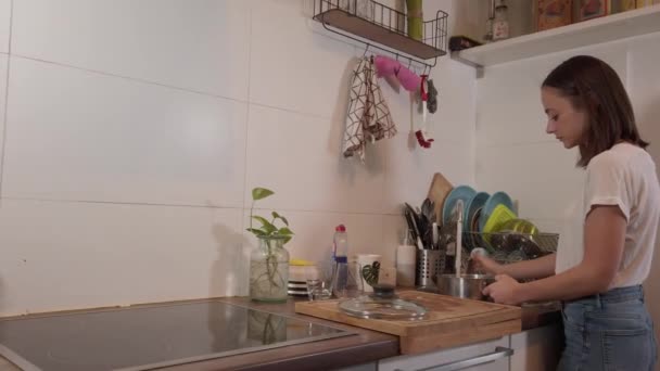 Mujer joven en la cocina prepara una olla para cocinar — Vídeo de stock