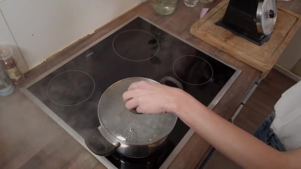 Young woman puts spaghetti into boiling water for cooking — Stock Video