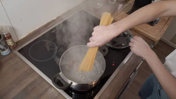 Young woman cooks spaghetti in the kitchen — Stock Photo, Image