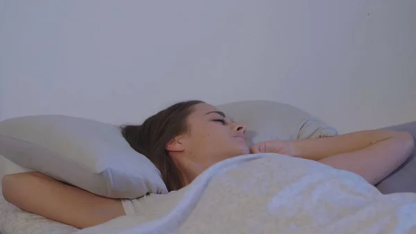 Jovem mulher em sua cama acorda de manhã cedo — Fotografia de Stock