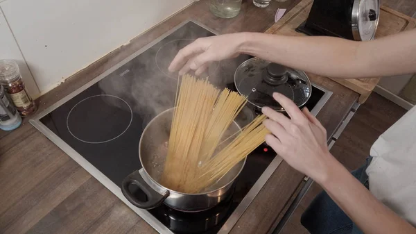 Mujer joven cocina espaguetis en la cocina —  Fotos de Stock
