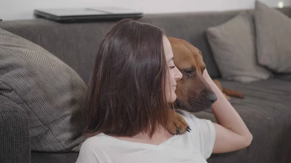 Young woman pets her dog while relaxing in the living room