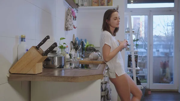 Tired girl in underwear drinks breakfast tea in the kitchen — Stock Photo, Image