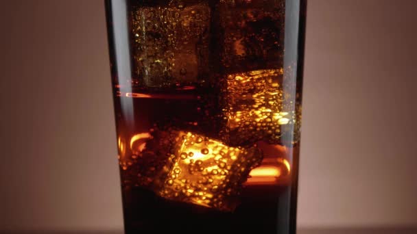 Um copo de Cola refrescante com cubos de gelo flutuantes — Vídeo de Stock