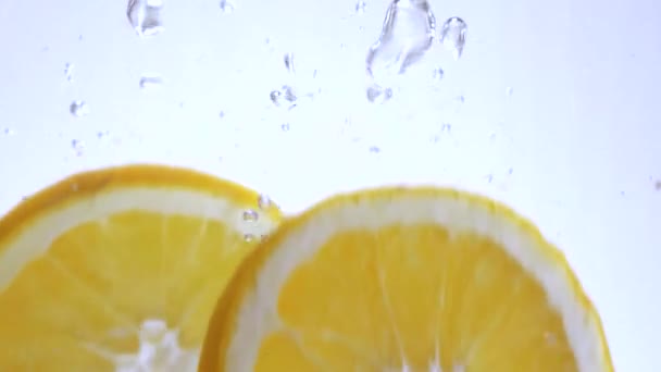 Close up shot of orange slices falling into water — Stock Video