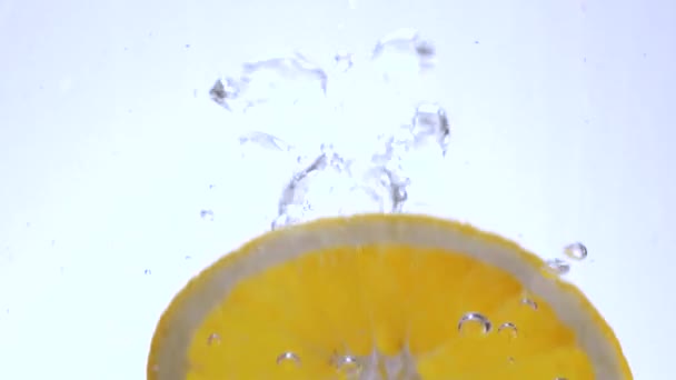 Primer plano de rodajas de naranja cayendo en el agua — Vídeo de stock