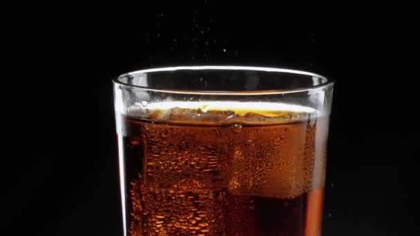 Les glaçons flottent dans un verre de cola rafraîchissant — Video