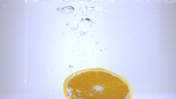 Tranches d'orange tombent dans l'eau au ralenti — Video