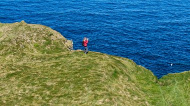 İrlanda'da iki kız güneşli bir günde Kilkee kayalıklarında yürümek - hava drone görünümü - seyahat fotoğrafçılığı