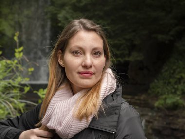 İrlanda 'da bir şelalenin önündeki genç kadın.