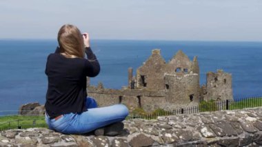 Genç kadın Kuzey İrlanda'da Dunluce Kalesi fotoğrafları çeker - seyahat fotoğrafçılığı