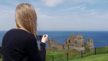Genç kadın Kuzey İrlanda'da Dunluce Kalesi fotoğraflarını çeker  