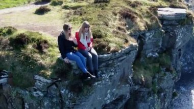 İki kız İrlanda'da Moher ünlü Cliffs kenarında oturup 