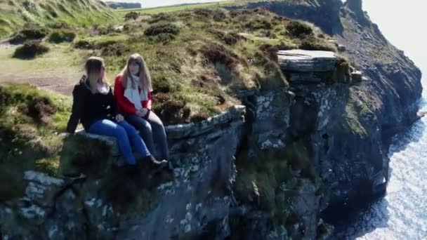 Две Девушки Сидят Краю Знаменитых Скал Мохера Ирландии — стоковое видео