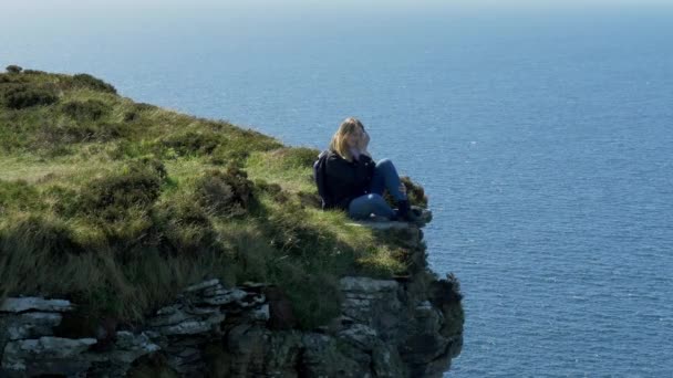 Jonge Vrouw Zittend Aan Rand Van Een Klif Aan Ierse — Stockvideo