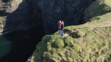 İki kız İrlanda'nın batı kıyısında bir uçurumun kenarında durmak  