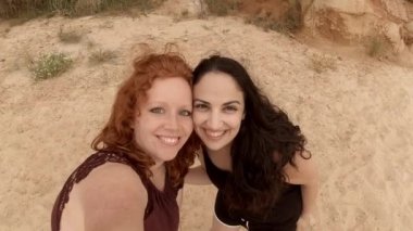 Arkadaşlar Portekiz 'de kumlu bir plajda selfie çekiyorlar.